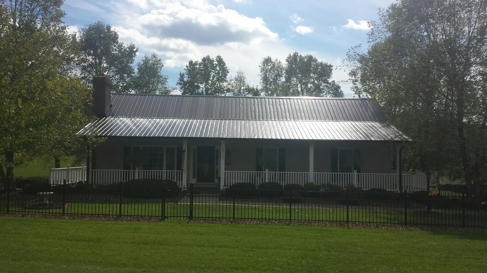 Gray metal roof on a brick ranch with a full width front porch — Gutter Guard Installation work by our crew in Soda Springs