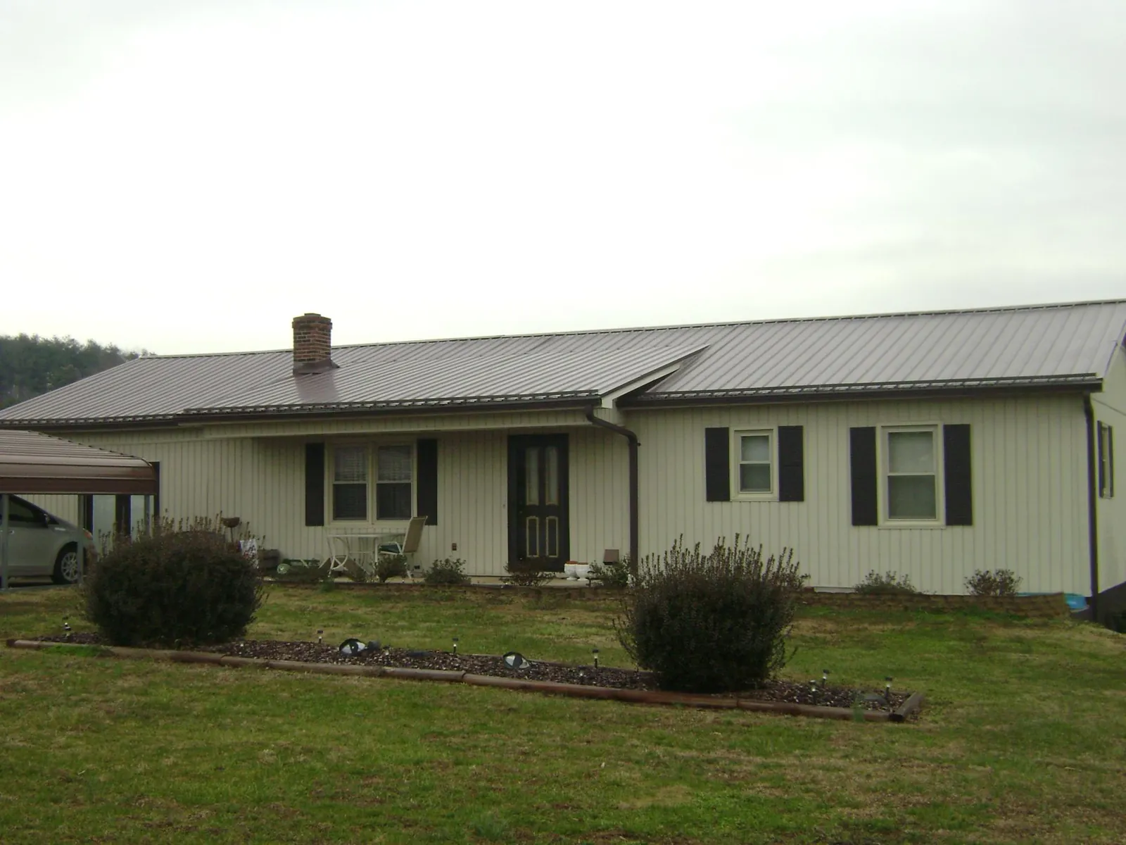 Brown metal roof on a cream sided ranch home with a brick chimney in Soda Springs